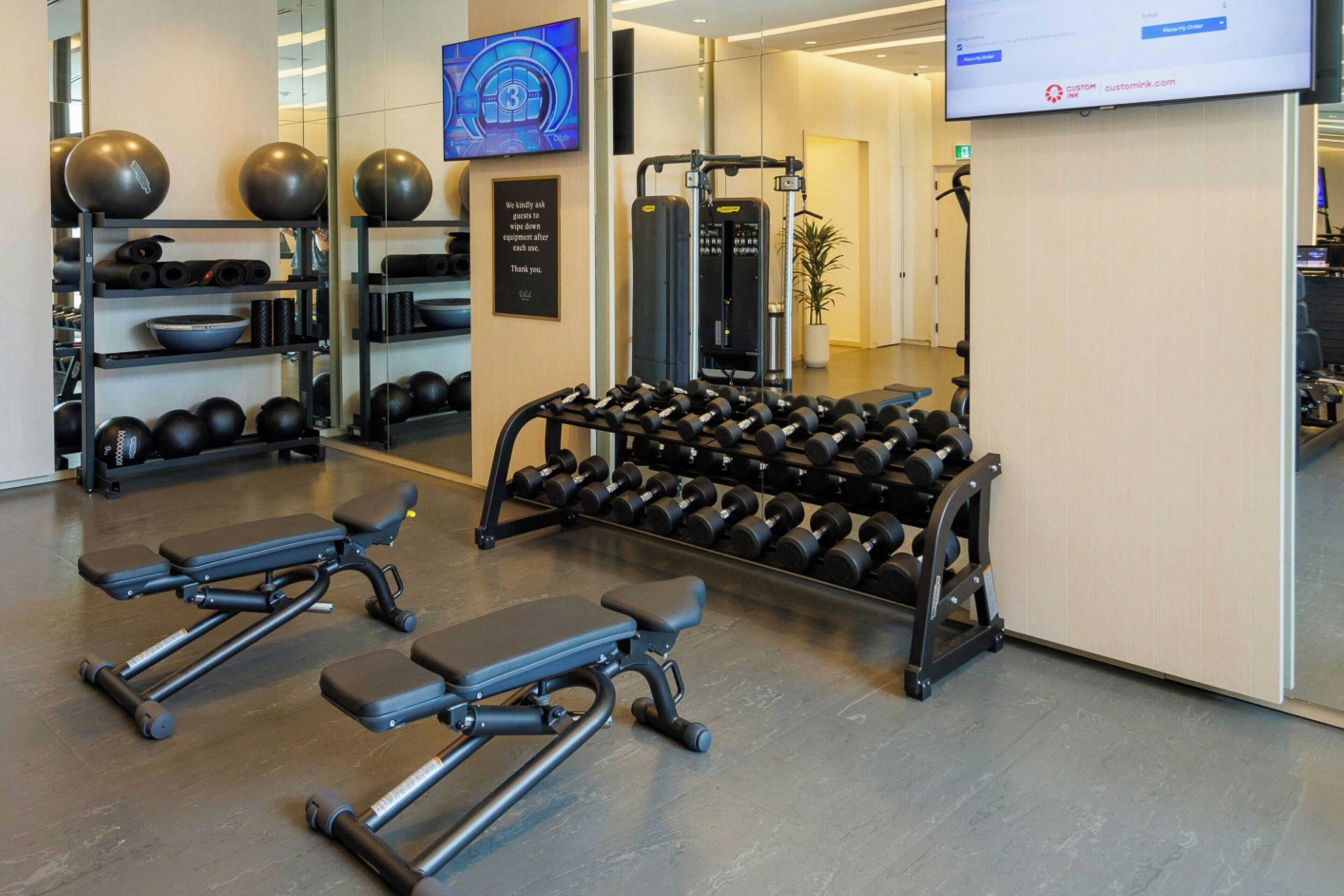 A gym with exercise equipment, a television, and a wall-mounted sign.