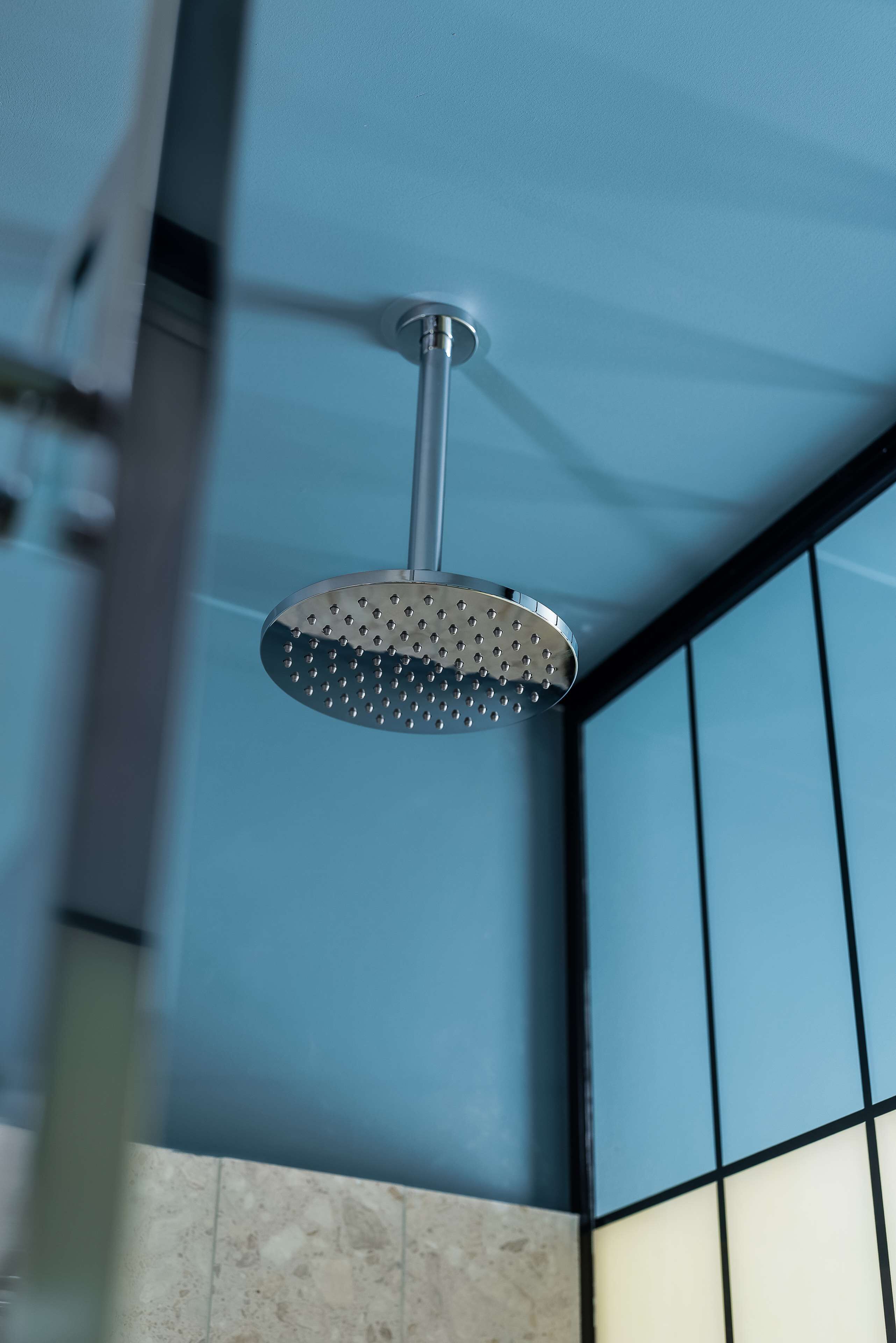 A showerhead in a bathroom with blue walls and a tiled floor.