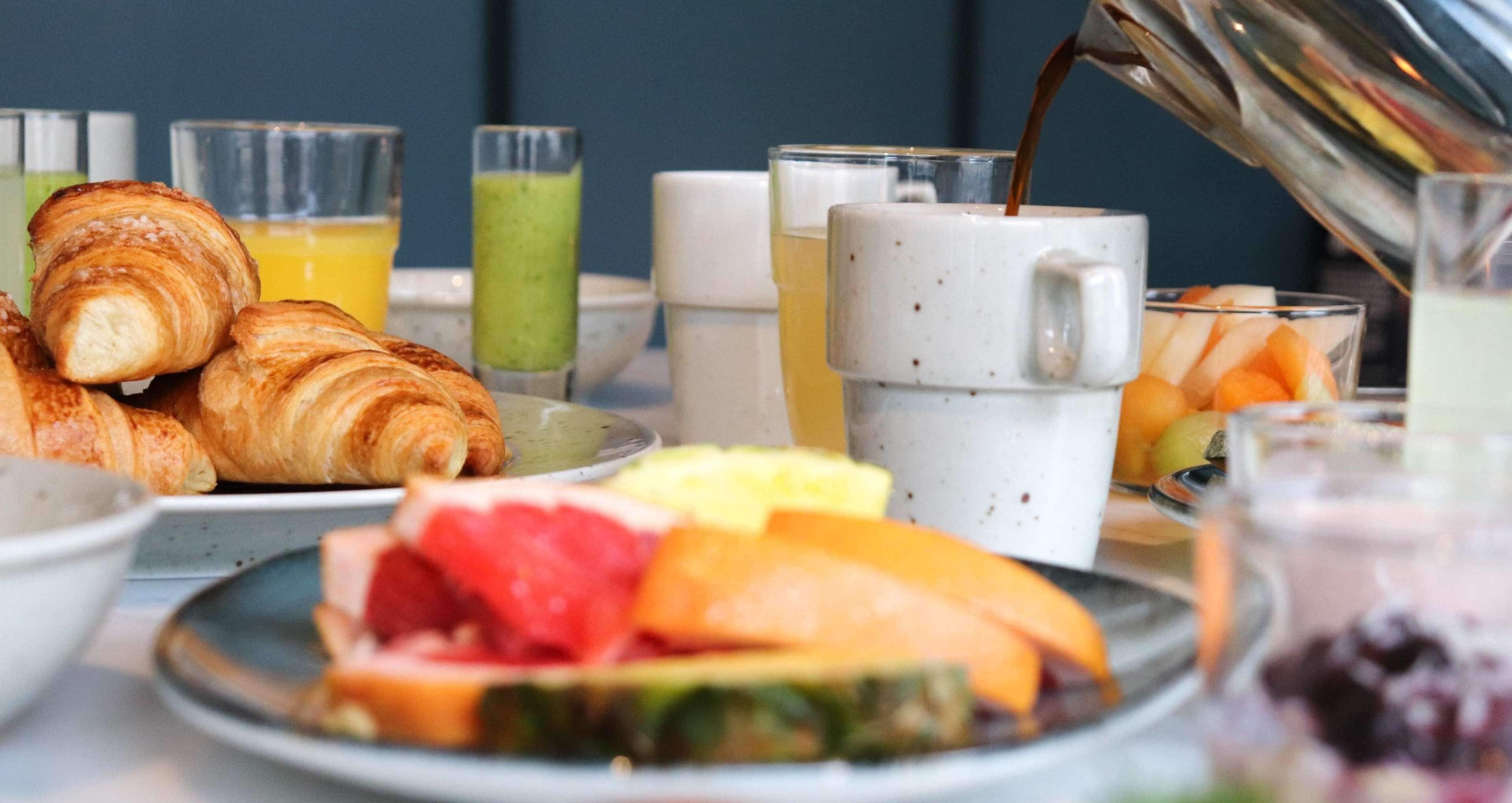 A breakfast setting with croissants, fruit, and beverages.