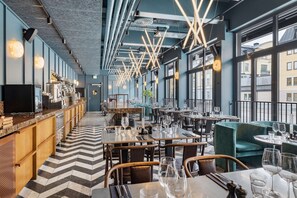 A modern restaurant with a long counter, multiple tables, and a patterned floor. - Best Western and Hotel Linkoping (Linkoping)