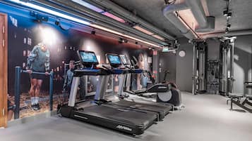 A gym with treadmills, a wall with a fitness poster, and exercise equipment.