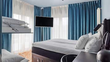 Una habitación de hotel con literas, un escritorio con silla, un televisor de pantalla plana y un teléfono.