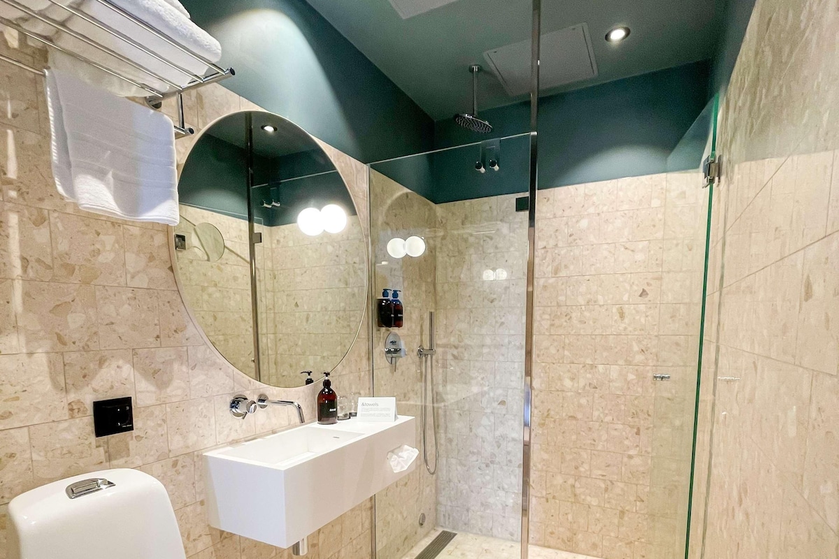 A modern bathroom with a toilet, sink, and glass-enclosed shower.