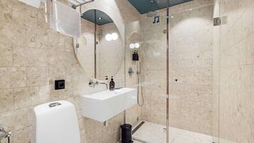 Un baño moderno con lavamanos blanco, espejo y cabina de ducha de vidrio.