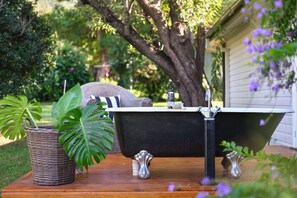 A bathtub on a wooden deck with a potted plant and a towel.