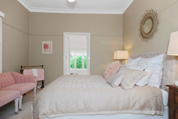 A bedroom with a bed, a chair, a window, and a mirror.