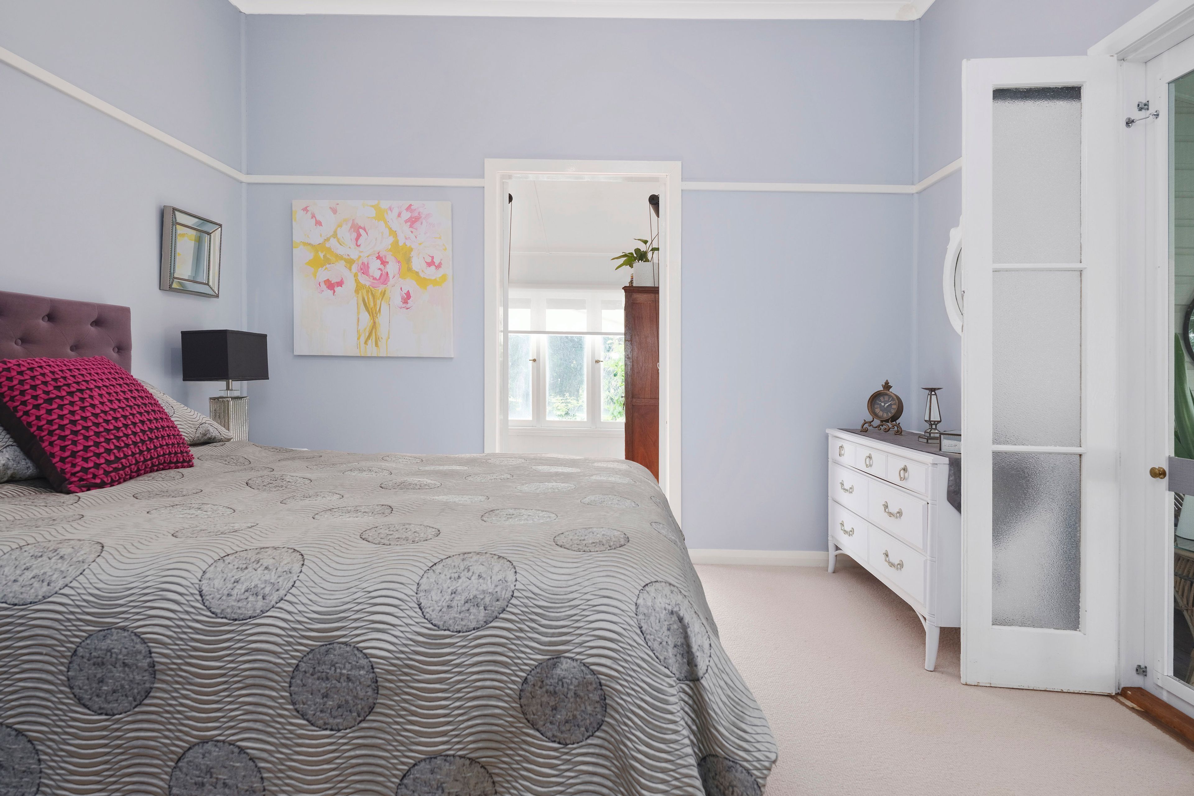 A bedroom with a bed, dresser, and a painting on the wall.