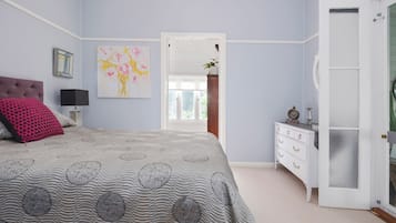 A bedroom with a bed, dresser, and a painting on the wall.