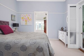 Une chambre à coucher avec un lit, une commode et un tableau accroché au mur.