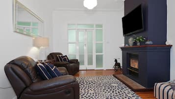 A living room with a fireplace, leather sofa, and a television mounted on the wall.