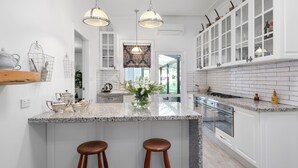 Una cocina moderna con una isla grande, iluminación colgante y armarios blancos.