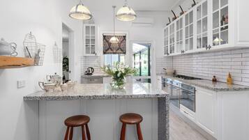 A modern kitchen with a large island, pendant lighting, and white cabinetry.