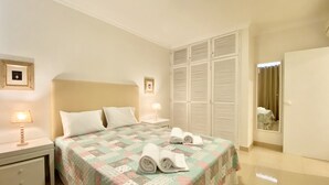 A neatly arranged bedroom with a bed, two bedside tables, a wardrobe, and a mirror. - Tália XI - Near the beach - Vilamoura (Vilamoura)