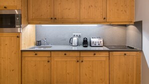 Una cocina con gabinetes de madera, microondas integrado, cafetera y tostadora.