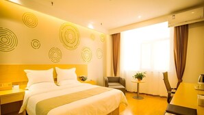 A hotel room with a large bed, a desk, and a chair. There are decorative wall patterns and a window with curtains. - Greentree Inn Jinzhong Yuci Old Town (Jinzhong)