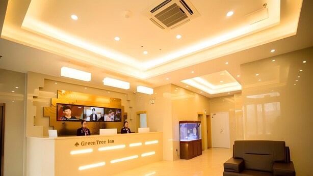 A reception area with a reception desk, a television, and a seating area with a sofa and a coffee table. - Greentree Inn Jinzhong Yuci Old Town (Jinzhong)