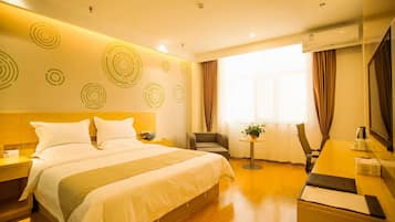 Habitación de hotel con una cama grande, un escritorio, una silla y una mesita con una planta.