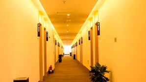 A long, well-lit hotel hallway with numbered doors and potted plants. - Greentree Inn Jinzhong Yuci Old Town (Jinzhong)
