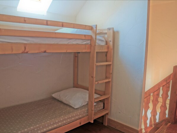 A bunk bed with a wooden ladder and a small shelf.
