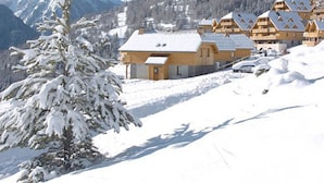 A snow-covered mountain with a row of wooden chalets. - Chalet in Pra Loup 1500 with 4 bedrooms for 12 people (Pra-Loup)