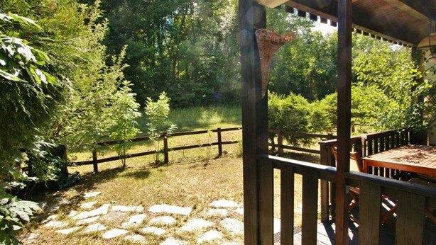 Un pontile in legno con un vialetto in pietra che conduce a un'area giardino recintata.