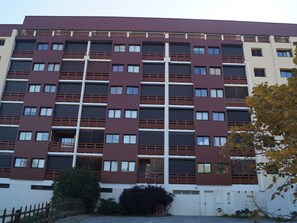 A multi-story building with a modern architectural design, featuring a series of balconies and windows.