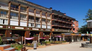 A multi-story hotel with balconies, outdoor seating, and various shops on the ground floor. - Spacious renovated T4 for 8 at Pra Loup 1600 (Pra-Loup)