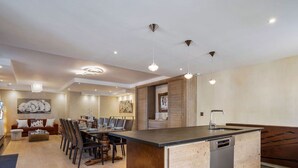 Una cocina moderna con una isla central, zona de comedor con sillas y sala de estar con sofá y obras de arte.
