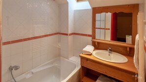 Un baño con tragaluz, una bañera, un tocador de madera con lavamanos y un espejo.