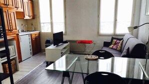 Een moderne keuken met houten kastjes, een eettafel met stoelen, een bank en een raam met natuurlijk licht.