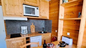 A compact kitchen with wooden cabinets, a microwave, a coffee maker, and a toaster. - Renovated studio at the foot of the slopes in Pra-Loup, ideal for 4 people (Pra-Loup)