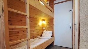 A wooden bunk bed room with a door and a light fixture. - Renovated studio at the foot of the slopes in Pra-Loup, ideal for 4 people (Pra-Loup)