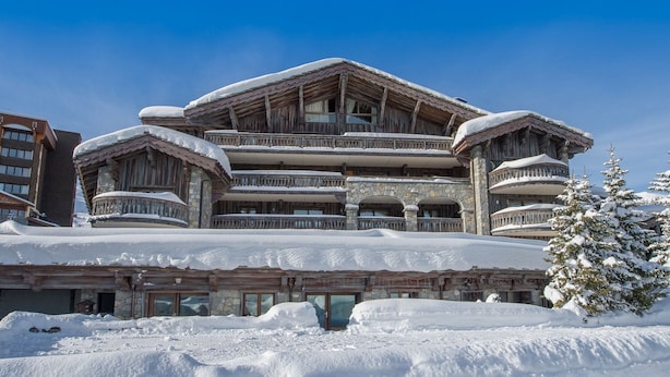 A large, multi-story building with a stone facade and wooden balconies, surrounded by snow. - Charming apt for 4 at the slopes - Pralong, Courchevel (Courchevel 1850)