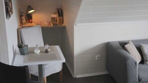 A room with a white table, a grey sofa, and a sloped ceiling. - Vacation apartment 1 - Apartments Riedel (Pegnitz)