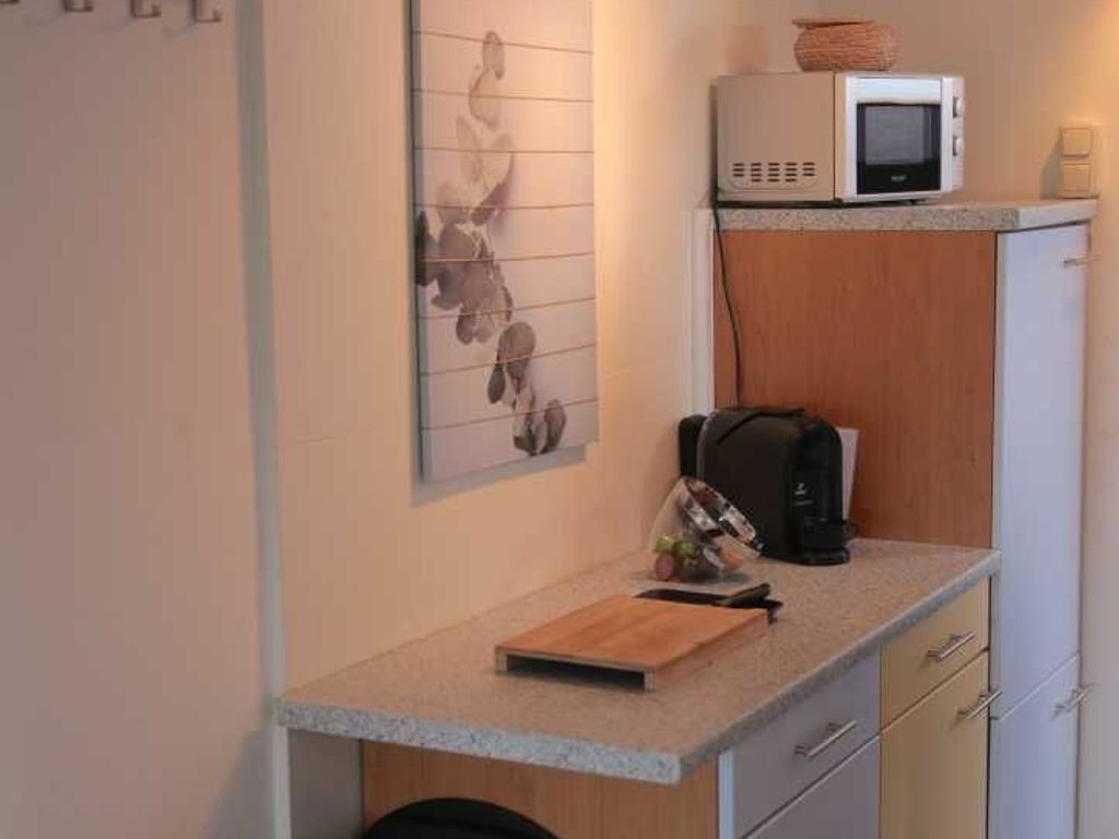 A compact kitchenette with a microwave, a small refrigerator, a cutting board, and a coffee maker.