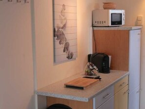 A compact kitchenette with a microwave, a small refrigerator, a cutting board, and a coffee maker. - Vacation Apartment 1 - Riedel Apartments (Pegnitz)