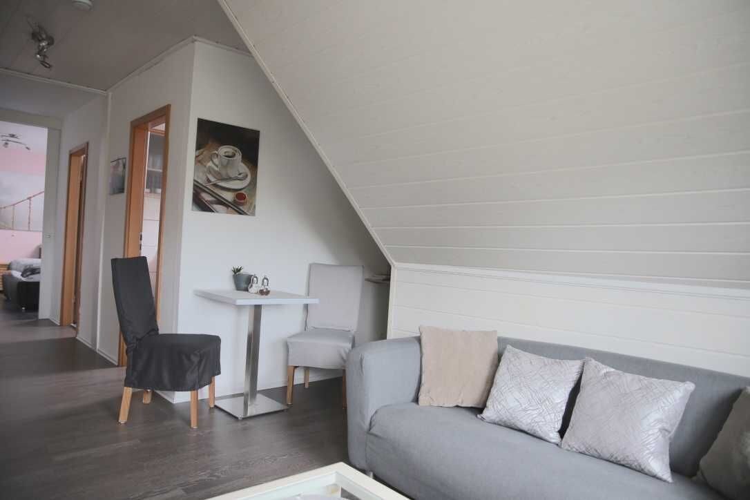 A modern loft-style room with a gray sofa, a small white table, and a black chair.