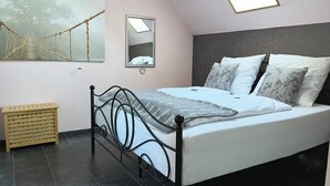 A bedroom with a bed, a mirror, a window, and a painting on the wall. - Vacation apartment 1 - Apartments Riedel (Pegnitz)