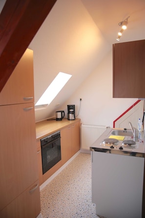 A compact kitchen with a skylight, a coffee maker, a sink, and a dishwasher.