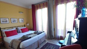 A bedroom with a bed, a desk with a keyboard, and a window with curtains. - Ca Barozzi (Venezia)