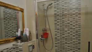 A bathroom with a shower, toilet, sink, and a mirror with a decorative frame. - Ca Barozzi (Venezia)