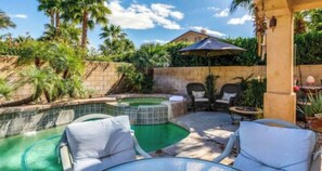 Un jardin avec une piscine, des chaises longues et un espace patio.