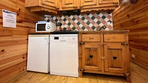 A compact kitchen with wooden cabinets, a microwave, a dishwasher, and a tiled backsplash.
