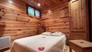 A wooden room with a bed, a wardrobe, and a window.