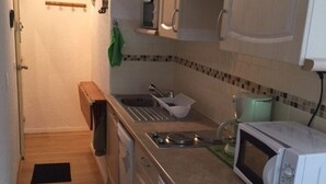 Une cuisine de taille réduite équipée d’un four à micro-ondes, d’un évier et de meubles de rangement en bois.