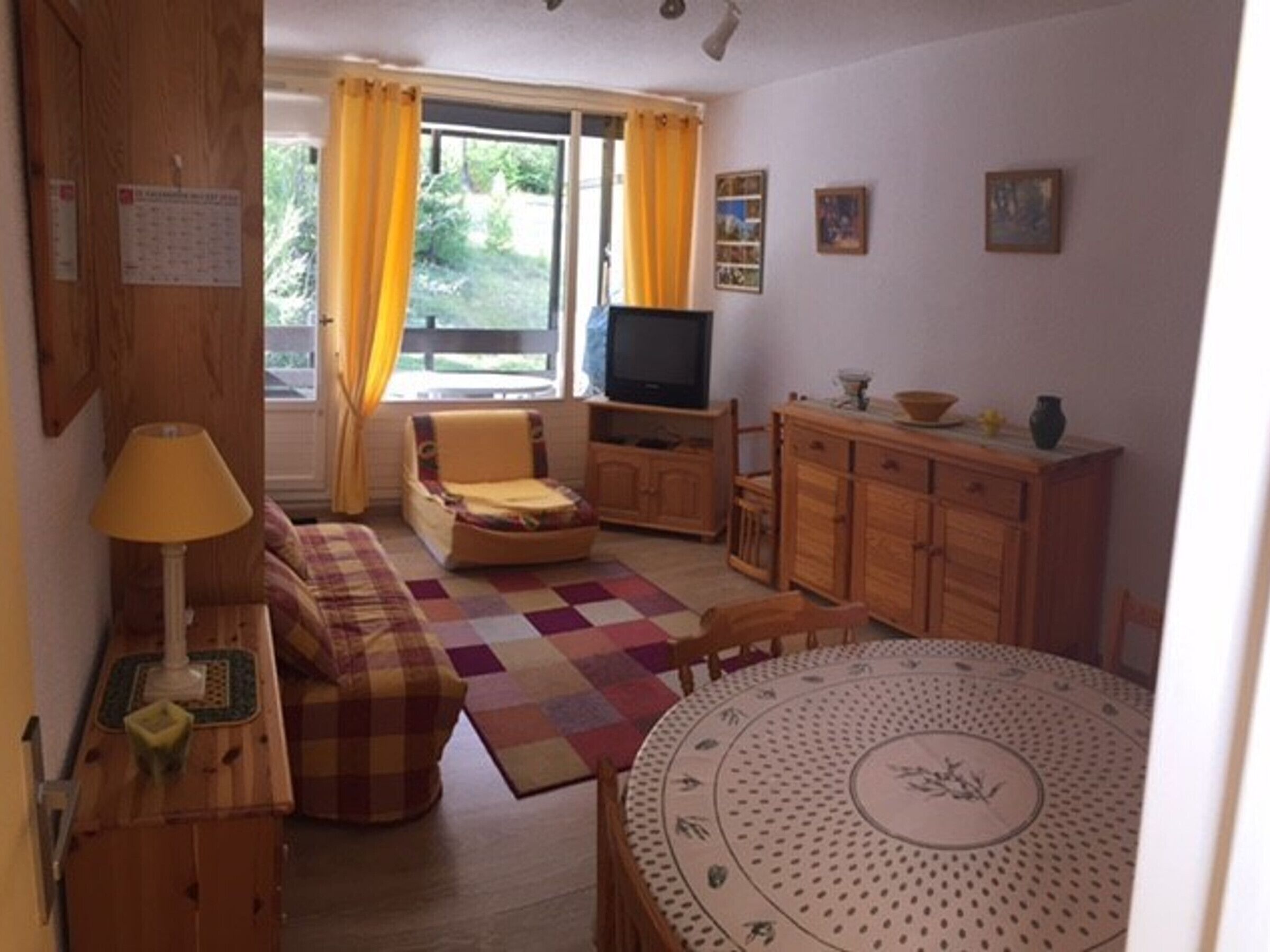 Ein gemütliches Wohnzimmer mit einer Couch, einem Sessel, einem Holzschrank und einem runden Tisch.