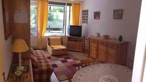 Un salon chaleureux avec un canapé, un fauteuil, un meuble en bois et une table ronde.