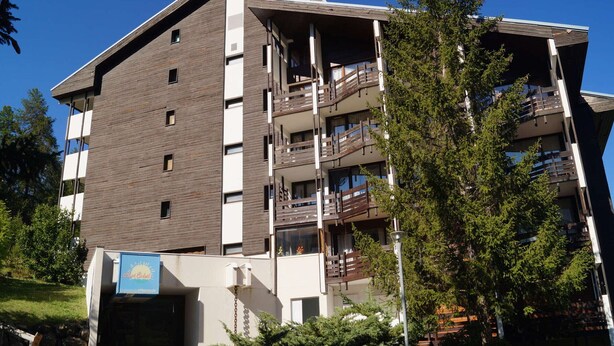 Un immeuble à plusieurs étages doté d’une architecture moderne, avec des balcons et une entrée de garage.