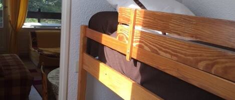 A small, cozy room with a bunk bed, a chair, and a table.