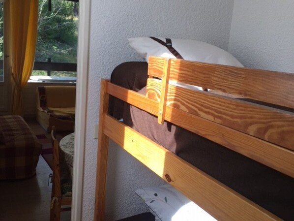 A small, cozy room with a bunk bed, a chair, and a table.
